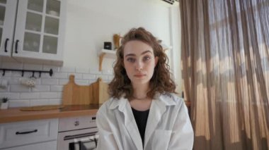 POV of woman evaluating birthday outfits of friend via video call showing displeased facial expression. Lady sits in kitchen looking in camera closeup