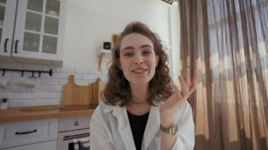 POV of woman sharing happy moment with relatives via video call sitting at kitchen table. Husband comes to wife looking in camera and smiling closeup