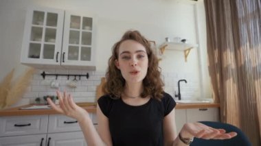 Woman talks to friends looking in camera on video call. Young lady turns to hug elderly mother coming into kitchen closeup from POV to third party