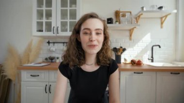 Woman talks to boyfriend on video call drinking tea. Young lady turns to mother to continue communication sitting at kitchen table from POV to third party