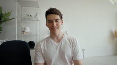 Young man talks to friend on video call distracting on mother coming into room. Happy guy turns to smiling elderly woman to hug from POV to third party