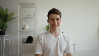 Young man talks to girlfriend on video call distracting on friend. Cheerful guy comes into room taking chair and shaking hands from POV to third party