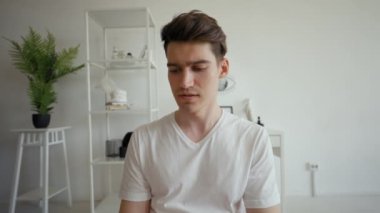 POV of young man taking online exam on video call from home. Male student sits in modern living room speaking and looking in camera close view
