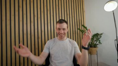 POV of emotional man enjoying conversation with friend on video call sitting at workplace. Young employee looks in camera talking in office closeup
