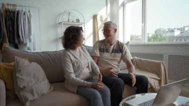 Happy senior couple talks to family psychologist on video call via laptop. Elderly man and woman hug showing thumb-up gesture after successful therapy