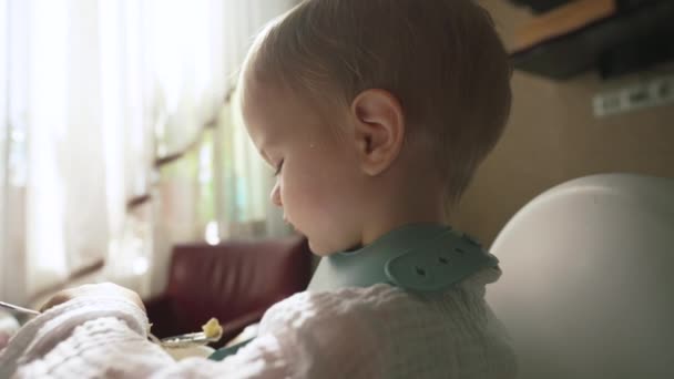 Blond Boy Eats Tasty Porridge Spoon Turning Camera Little Toddler — Stockvideo