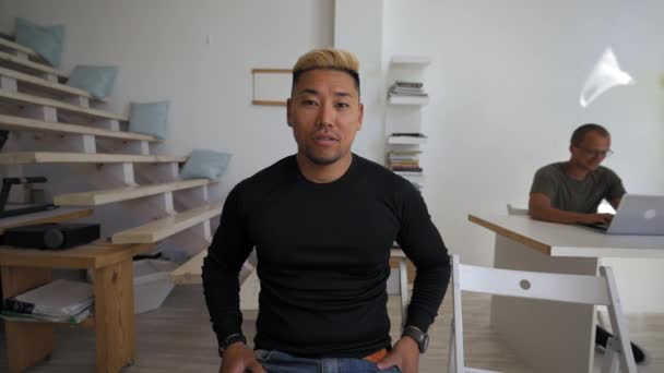 Asian Man Talks Camera Turning Greet Colleague Coming Sit Desk — Video
