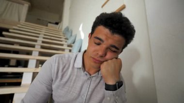 POV of male student feeling bored listening to mentor on online teaching conference. Tired guy sits at home trying to look in camera closeup