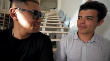 Guys friends enjoy communication sitting on stairs at home and shake hands saying goodbye. Man turns to camera to continue talking from third party to POV