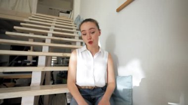 Woman talks to boyfriend on video call getting interrupted by best friend. Young lady sits on stairs talking with friend from POV to third party