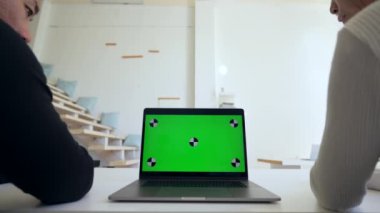 Men colleagues watch educational lessons on modern laptop sitting at desk in office. Open computer with chromakey screen closeup replace with Your content