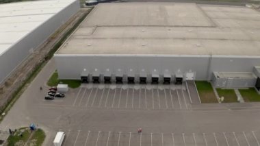 Engineers walk to check large storage terminal with loading docks for trucks. Industrial building and territory of logistics center aerial view
