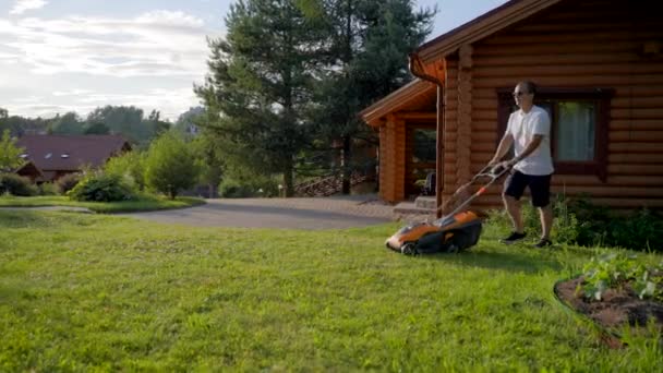 Mature Man Cuts Grass Using Petrol Lawnmower Wooden Cottage Middle — Stockvideo