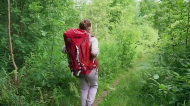 Young couple of hikers walks trying to find perfect spot for nice camping in forest. Young man and woman enjoy hiking together smiling to each other