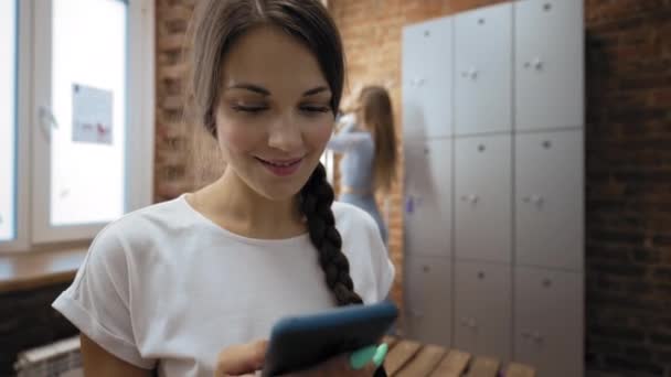 Woman Uses Phone While Girl Friend Makes Hairstyle Standing Mirror — Stockvideo