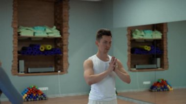 Profesyonel koç büyük salonda kadın öğrencileri karşılamak için yoga antrenmanı yapıyor. Genç adam ve bayanlar beden ve sağlık yakın çekim için etkili bir eğitimin keyfini çıkarıyorlar.