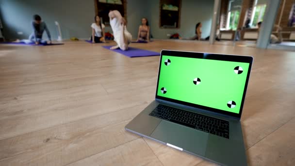 现代笔记本电脑与在瑜伽训练中锻炼的人格格不入 大型大厅特写镜头中带有绿色铬质屏幕的开放设备 — 图库视频影像