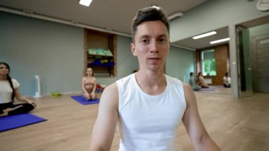 Profesyonel erkek koçun kamera karşısında minderlerde oturan kadınlara karşı duruşu. Adam, yoga eğitiminin yakın çekim videosunu kaydediyor.