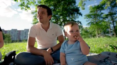 Küçük çocuk babasının yanına oturur ve lezzetli yemekler yer. Küçük çocuk çimenlerde oynamaktan ve meyve yemekten hoşlanıyor. Baba çubuğu kapar ve yürümeye başlayan çocukla oynar.