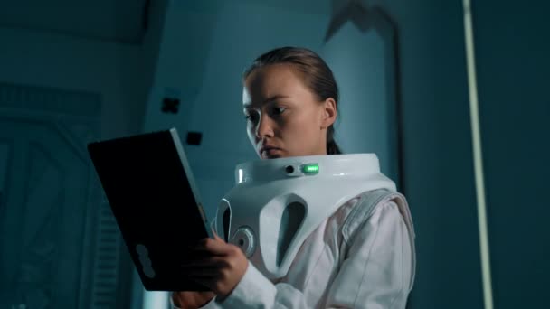 空间站上的一名女宇航员手里拿着一块石碑 在一艘未来派宇宙飞船内部的缓慢运动中 一位亚洲女孩太空旅游者在她的平板上检查了路线 — 图库视频影像
