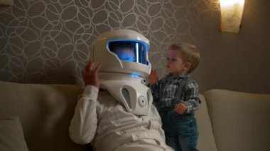 Sarışın bir oğul, babasının astronot kaskının camını çalar, bir adam ve bir çocuk, rahat bir apartmanın içinde astronotçuluk oynarlar..