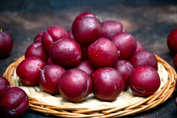 Les fruits frais de la prune rubis reposent sur un plateau en osier. — Photo