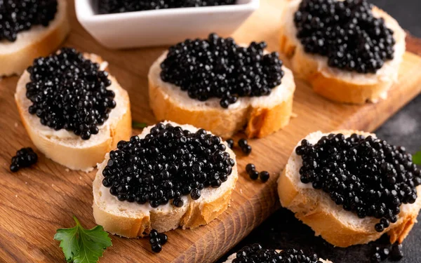 Rebanadas de pan con caviar negro sobre fondo rústico oscuro — Foto de Stock