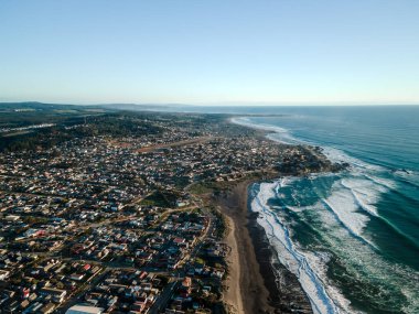 Gün batımında Pichilemu 'nun sokakları, sahili ve okyanus dalgalarıyla genel hava manzarası..