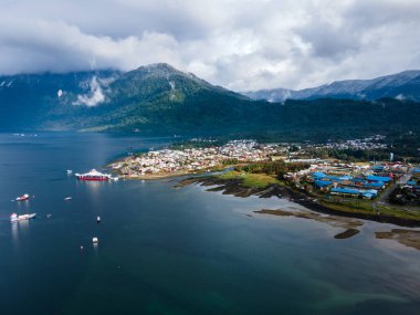 Kış günü güneş doğarken, karla kaplı dağları ve kıyılarındaki gemileriyle Hornopiren 'in hava manzarası..