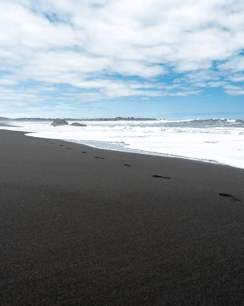 Vertikales Foto Von Fußabdrücken Schwarzen Sand Mit Blick Auf Die — Stockfoto