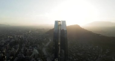 Santiago de Chile şehrinin arka planında ada tepeleri ve yan tarafında güneş ışığı olan hava yörüngesi..