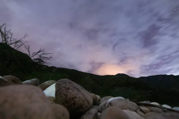 Bulutlu bir gecede nehir kenarında, yıldız nihayet gökyüzünde görünmeye başlar.