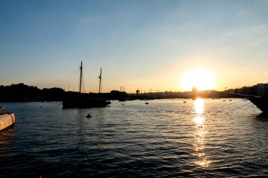 Sliema körfezine park etmiş bir yelken şeklinde gün batımı manzarası.