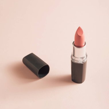 Gentle coral lipstick on soft pink background