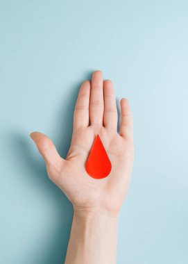 Minimalist concept of a red drop of blood on the palm