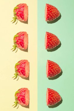 Çilekler sarı-yeşil arka planda ikiye bölünmüş. Dikey bileşim.