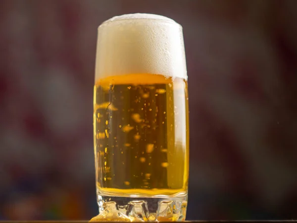 Glass of light beer on wooden ta