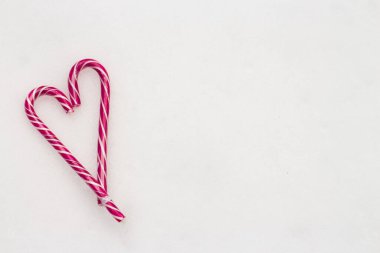 Bayramlık minimalist beyaz arka plan. Beyaz kar arka planında pembe çizgili şeker dolu bir kalp. Sevgi. - Valentine. Sevgililer Günü için yaratıcı hediye fikirleri. 14 Şubat 'ta. Fotoğraflı.