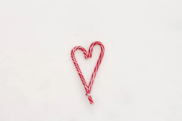 Fondo blanco minimalista festivo. Un corazón de dulces caramelos de rayas rojas sobre un fondo de nieve blanca. Amor. Ideas de regalos creativas para San Valentín. El 14 de febrero. Foto con espacio para —  Fotos de Stock