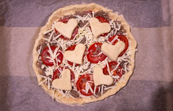 Pizza caseira festiva com carne, tomate e queijo decorado com corações de massa. Jantar romântico do Dia dos Namorados. Pizza artesanal para o Dia dos Namorados. — Fotografia de Stock