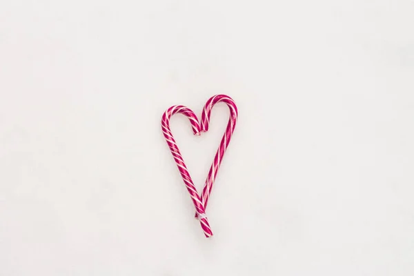 Festlicher minimalistischer weißer Hintergrund. Ein Herz aus süßen rosa gestreiften Bonbons auf weißem Schneehintergrund. Liebe. Valentinstag. Kreative Geschenkideen zum Valentinstag. Der 14. Februar. Foto mit einem — Stockfoto