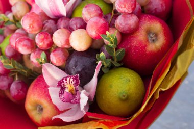 Erikli, üzümlü, narlı, limonlu ve pembe canlı orkideli meyveli, yenilebilir kırmızı elma buketi..