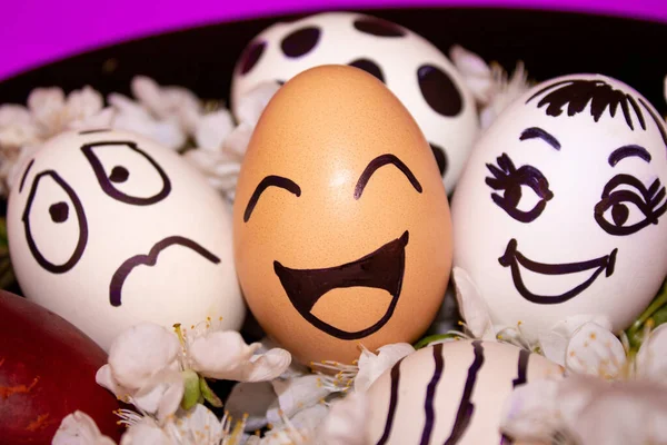 Веселі великодні яйця з пофарбованими смайликами та білими квітами поруч з ними. Святкування. Великодні яйця з радісними обличчями на тарілці. Великдень своїми руками. Концепція мінімального великодніх свят — стокове фото