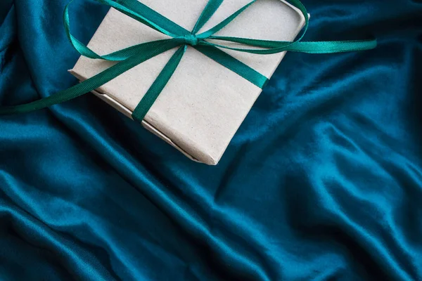 Zümrüt yeşili saten kurdeleyle sarılı bir hediye kutusu. - Mutlu yıllar. İpek zümrüt yeşili arka planda doğum günü hediyesi