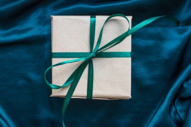 Zümrüt yeşili saten kurdeleyle sarılı bir hediye kutusu. - Mutlu yıllar. İpek zümrüt yeşili arka planda doğum günü hediyesi