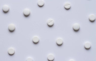 Beyaz arka planda bir sürü beyaz tablet ya da hap var. Tıbbî eczane ve ilaç konsepti. Beyaz yuvarlak haplar dağılıyor. Yüksek kalite fotoğraf