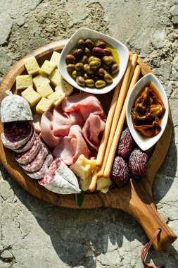 İtalyan aperatifi ve kırmızı şarap: prosciutto, salam, güneşte kurutulmuş domates, zeytin, peynir, Grissini ve hurma. Sokakta yaz atıştırması