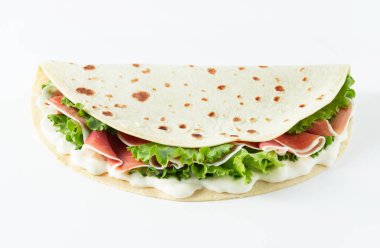 İtalyan sokak yemekleri bembeyaz arka planda piadina yatıyordu. Piadina Romagnola - İtalyan düz ekmeği jambon, salata ve krem peynirli