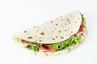 İtalyan sokak yemekleri bembeyaz arka planda piadina yatıyordu. Piadina Romagnola - İtalyan düz ekmeği jambon, salata ve krem peynirli