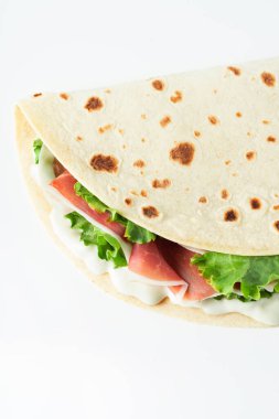İtalyan sokak yemekleri bembeyaz arka planda piadina yatıyordu. Piadina Romagnola - İtalyan düz ekmeği jambon, salata ve krem peynirli
